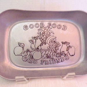 Könnte beinhalten: Ein silbernes Serviertablett mit einem erhabenen Design aus Früchten und dem Text "GOOD FOOD GOOD FRIENDS".
