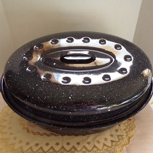 May include: A black and white speckled oval roaster with a lid. The lid has a silver handle and a ring of silver dots around the edge.
