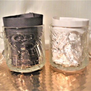 May include: Two clear glass mugs with a textured design. One mug has a dark design inside and the other has a light design inside.