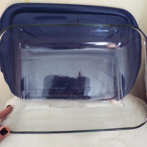 May include: A clear glass baking dish with a blue lid. The dish is empty and ready to be used for baking.