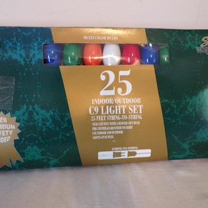 May include: A rectangular box for a 25-count C9 indoor/outdoor light set by Santa's Workshop. The dark green packaging features a window displaying multi-coloured bulbs, gold accents, and text detailing 25 feet of string-to-string lighting.