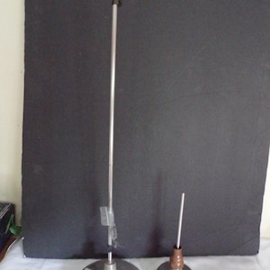 May include: Two metal stands with circular bases. One is tall with a thin, silver pole and a small, clear tag. The other is shorter with a brown and silver top and a thin, silver pole.