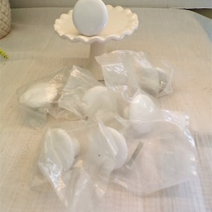 May include: A set of six white ceramic cabinet knobs with silver screws. The knobs are packaged in clear plastic bags.