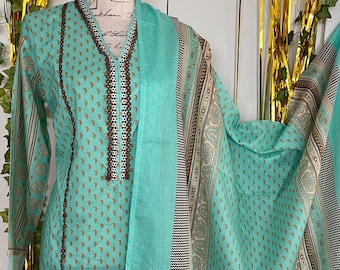 May include: A turquoise blue and gold patterned dress with a long sleeve and a matching dupatta. The dress has a V-neckline and a decorative trim around the neckline.