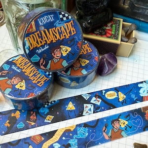 May include: Blue washi tape rolls and strips with a cartoon theme. The rolls are labeled "DREAMSCAPE" and "Kaycat Washi." The tape features illustrations of characters, books, and other graphic elements. The background is a dark blue with stars.