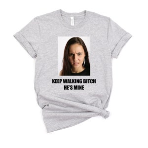 May include: Gray t-shirt with a photo of a woman with a serious expression and the text "KEEP WALKING BITCH HE'S MINE".