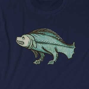 May include: A navy blue t-shirt with a green and white illustration of a fish with legs. The fish is facing left and has a large mouth.