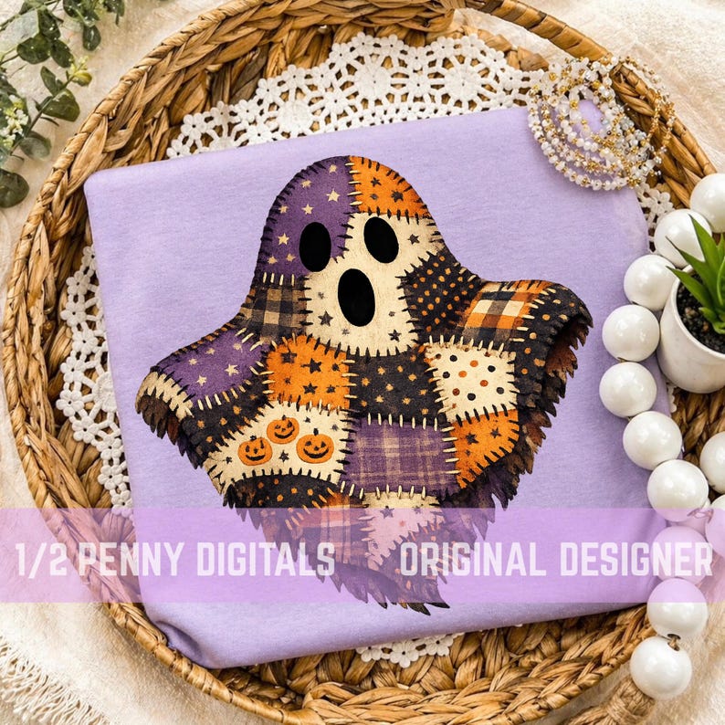 May include: A light purple t-shirt featuring a central graphic of a ghost composed of various patchwork squares in orange, black, and purple patterns, including stars, pumpkins, and plaid. The text 1/2 PENNY DIGITALS ORIGINAL DESIGNER is visible.