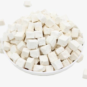 May include: A white bowl filled with small, white, cube-shaped pieces of dried Poria cocos, a type of medicinal mushroom.