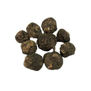 May include: A group of dried black maca root pieces. The pieces are irregularly shaped and have a dark brown color.