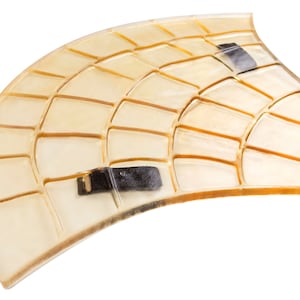 Puede incluir: Un molde de plástico transparente con un patrón de cuadrícula, diseñado para crear caminos de concreto. El molde tiene dos asas negras.