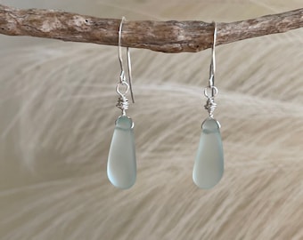 May include: A pair of silver dangle earrings with light blue teardrop-shaped glass beads.