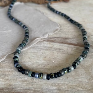 May include: A black, gray, and silver beaded necklace with a variety of patterned beads.