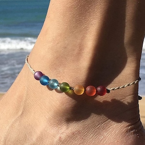 May include: A rainbow anklet with colorful glass beads on a white cord.