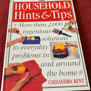 May include: A hardback book titled "HOUSEHOLD Hints & Tips" with red and white text. The cover features illustrations of household solutions and the author's name, Cassandra Kent. The book promises over 2,000 ingenious solutions to everyday problems.