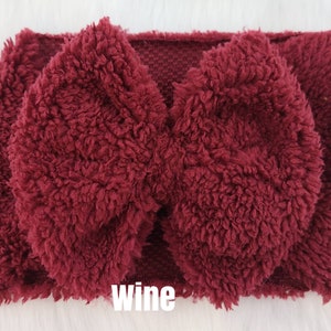 May include: A burgundy fuzzy headband with a large bow. The headband is made of a soft, plush material and is perfect for keeping your ears warm in the winter.