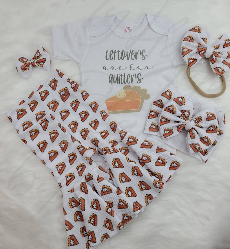 May include: A white baby onesie with the text "Leftovers are for quitters" and a pie graphic. The onesie is paired with a white headband and a pair of white trousers with a pie pattern.