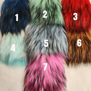 May include: A collection of faux fur fabric swatches in various colors. The colors include dark blue, mint green, red, light blue, gray, brown, and pink. Each swatch has a fluffy, textured appearance, with visible fibers and a gradient effect.