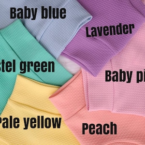 May include: Six fabric swatches in various pastel colors, including baby blue, lavender, pastel green, pale yellow, peach, and baby pink. The swatches are arranged in a circle.