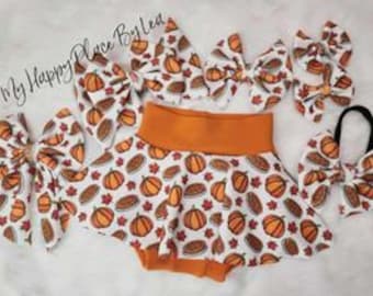 May include: A set of four orange and white pumpkin and pie print hair bows with a matching orange and white pumpkin and pie print ruffle skirt and headband.