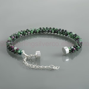 May include: A bracelet composed of small, faceted green and magenta zoisite beads arranged in a dense, textured band. The piece features a silver-toned magnetic clasp and an adjustable silver-toned chain link extender for a secure fit.