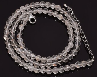 May include: A necklace composed of round, translucent, clear quartz beads with subtle internal inclusions. The strand features a silver-toned metal lobster claw clasp and a short adjustable chain extension at the end for length customization.