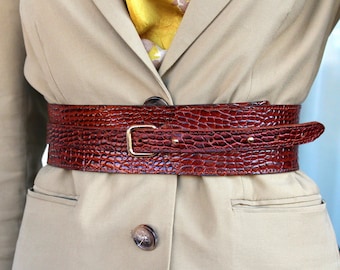 May include: A tan blazer with a brown crocodile-embossed belt. The belt has a gold buckle.