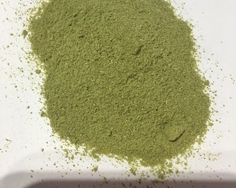 May include: A pile of light green powder on a white surface.