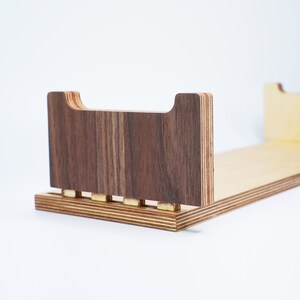 May include: A wooden shelf unit with a brown wood front and a light wood back. The shelf is made of plywood and has a simple design.