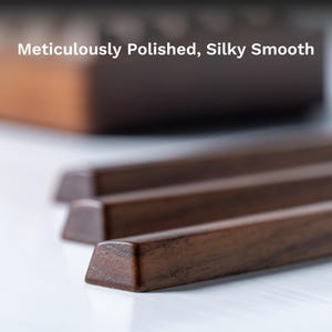 May include: Close-up of three rectangular, dark brown wooden pieces with angled ends. The wood has a polished, smooth finish. Text at the top reads "Meticulously Polished, Silky Smooth."