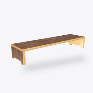 May include: A wooden shelf with a dark brown top and light brown sides. The shelf is designed to be mounted on a wall and has a simple, modern design.