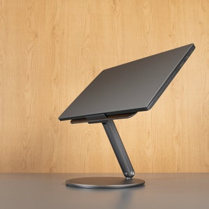A display of a laptop stands against a wood-colored background.