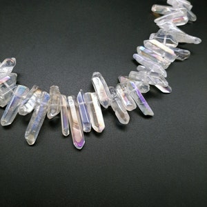 Pode incluir: Um fio de contas de cristal de ponta branca iridescente. As contas s&atilde;o facetadas e t&ecirc;m um brilho arco-&iacute;ris. As contas s&atilde;o enfiadas em um cord&atilde;o el&aacute;stico transparente.