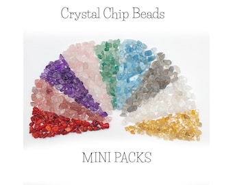May include: Assortment of colorful crystal chip beads in a rainbow fan shape. The beads are small and irregular in shape. The colors include pink, purple, green, blue, gray, white, and yellow. The text "MINI PACKS" is written below the beads.