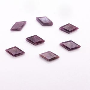 May include: Eight purple diamond-shaped gemstones on a white background.