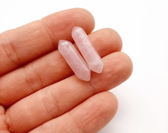 Puede incluir: Dos puntas de cristal de cuarzo rosa pálido con un agujero perforado en la parte superior para hacer joyas.