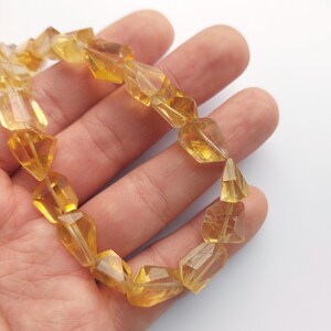 May include: A bracelet made of faceted, yellow citrine beads. The beads are strung on a clear elastic cord and are approximately 10mm in diameter.