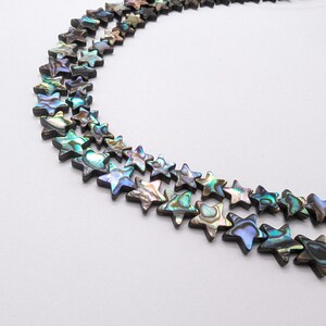 May include: A strand of iridescent abalone shell star-shaped beads. The beads are a mix of blue, green, and brown colours.
