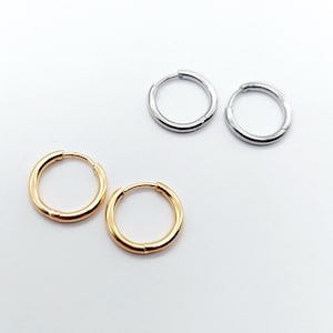May include: Three pairs of hoop earrings, two silver and one gold. The earrings are all the same size and style.