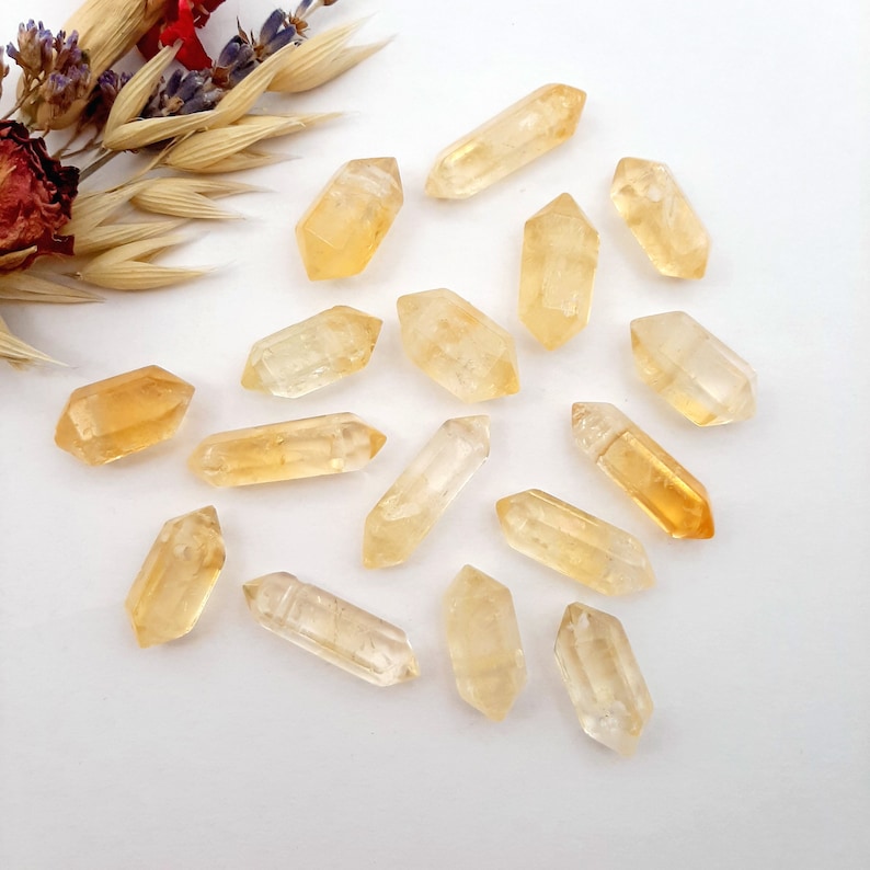 May include: A collection of 17 small, pointed, golden citrine crystals. The crystals are arranged in a heart shape on a white background.