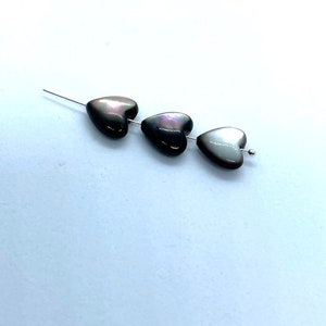 May include: Three iridescent black heart-shaped beads strung on a silver wire.