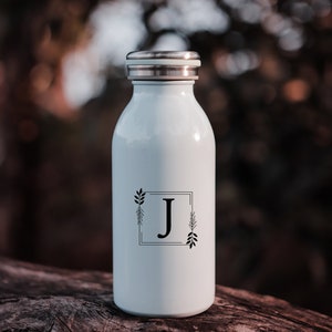 May include: White stainless steel water bottle with a black and white floral design and the letter "J" in a square frame.