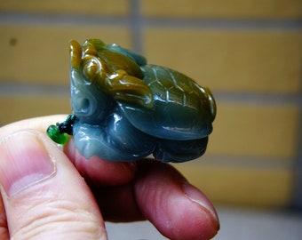 May include: A jade green and yellow carved turtle pendant. The turtle is detailed with a textured shell and a carved head.