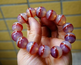 May include: A bracelet made of round, red and white agate beads. The beads have a striped pattern.