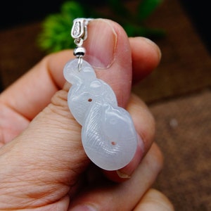 May include: White jade pendant carved in the shape of a knot. The pendant is attached to a silver chain.