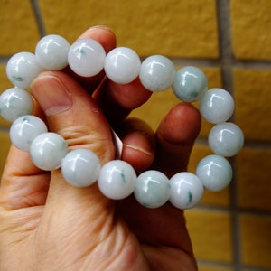 May include: A jade bracelet featuring white and green beads. The bracelet is crafted from natural jade and has a smooth, polished finish.