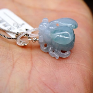 May include: A delicate jade pendant necklace featuring a carved jade pendant in the shape of a mythical creature. The pendant is a light blue-green colour and has intricate details. The necklace is made of silver and has a lobster clasp.