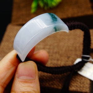 May include: A white jade bracelet with a green jade accent. The bracelet is made of smooth, polished jade and has a simple, elegant design.