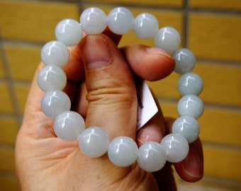 Könnte beinhalten: Ein weißes Jade-Armband mit runden Perlen. Das Armband ist aus natürlichem Jade gefertigt und hat eine glatte, polierte Oberfläche.