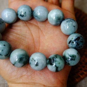 May include: A jade bracelet featuring green and black mottled beads. The bracelet is crafted from natural jade and has a polished finish.